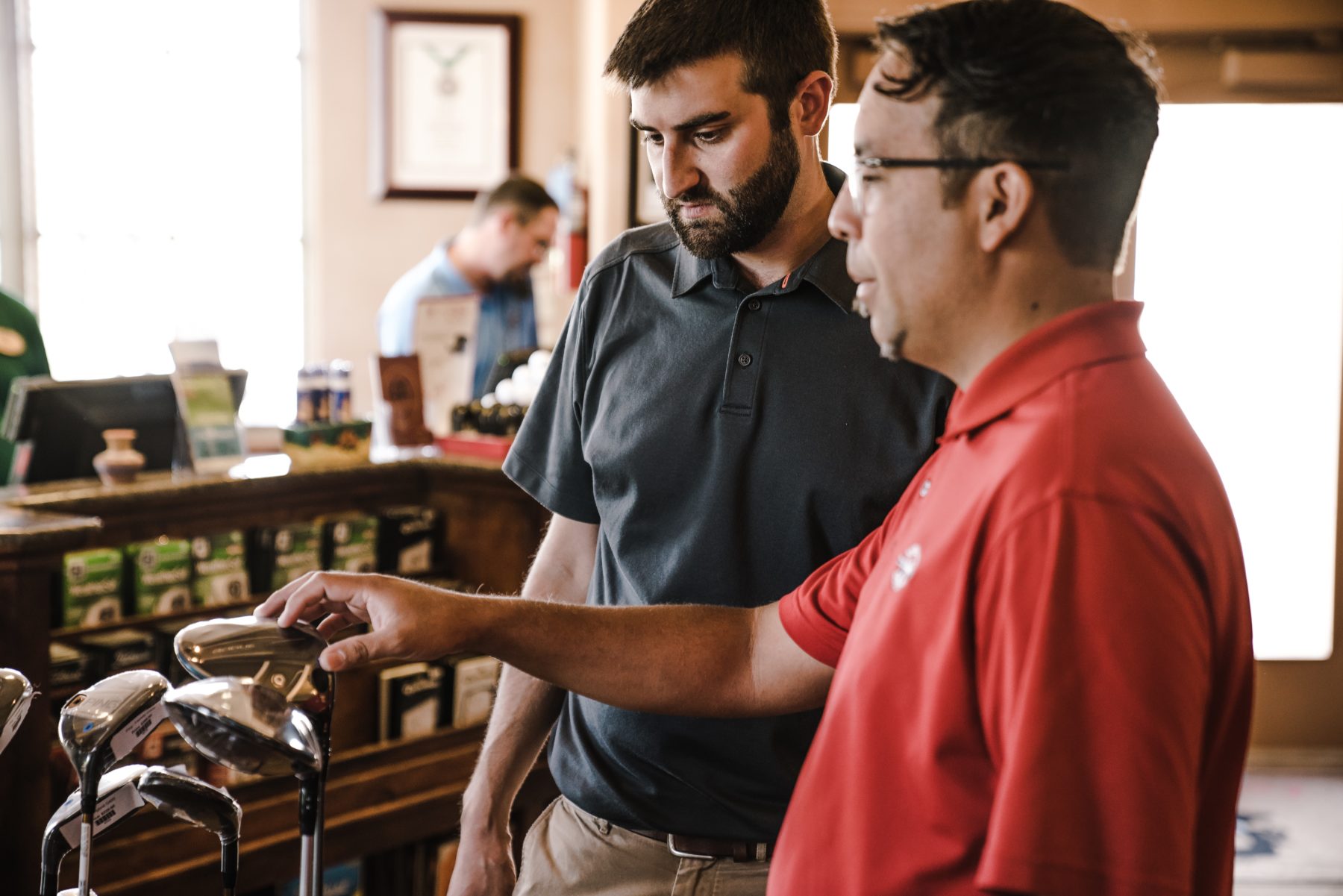 Two men standing looking at a set of golf clubs