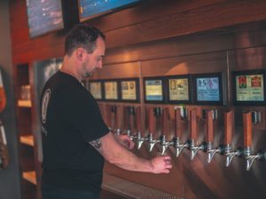A man fills his glass at a self-pour tap wall.