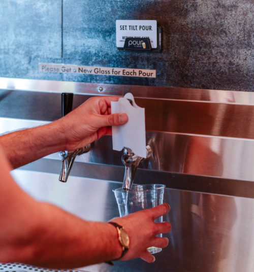 Pouring from PourMyBeer self-serve beverage wall with Tapkin